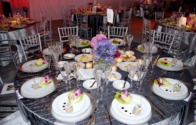 Tables in the main dining area were draped with pewter and white linens, surrounded by silver Chiavari chairs, and accented with arrangements of purple, pink, blue, and soft green flowers.