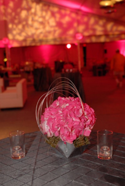 Low centerpieces featuring greenery painted silver to resemble metal were placed atop gunmetal-colored linens.