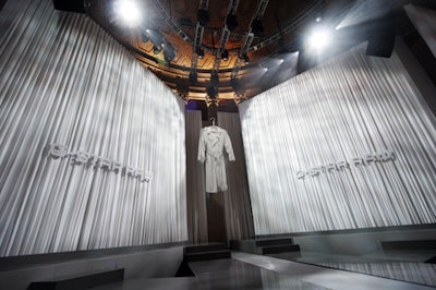 An oversize white denim coat hung over G-Star's runway, flanked by long white drapes. The coat was a playful reference to the brand's reputation for making large denim items such as covers for cars and motorcycles.