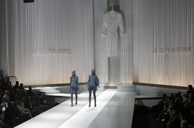 Part of the show's choreography included one model standing on the runway's conveyor belt while another, in a simliar outfit, walked alongside.