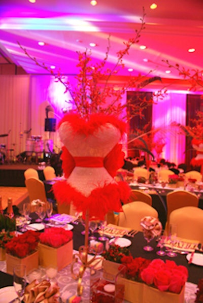 Each table featured a series of bust forms with elaborate feather bustle details and a vignette of various flowers, including roses and orchids.