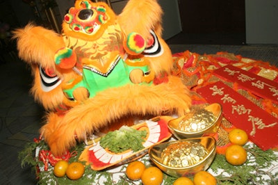A Chinese New Year display featured a lion head surrounded by good-luck lettuce, gold coins, and mandarin oranges.