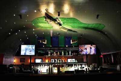 The main bar inside Greenwich Village Country Club has a ceiling decorated to look like a putting green on a miniature golf course. The section is enclosed in walls that feature a lattice of metal golf clubs.