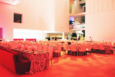 Washed in red lighting, the dinner space mixed round tables with long banquet tables and chairs with plush couches.