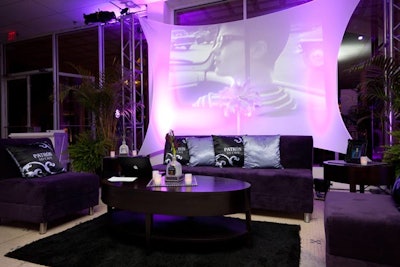 Clips of old black-and-white movies played on white draping hung behind furniture from AFR Event Furnishings.