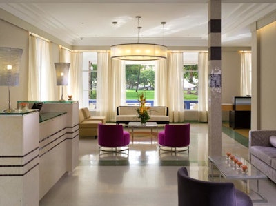 The white-and-cream-colored lobby is complemented by purple seating and different lighting fixtures.