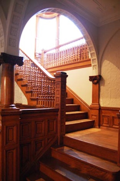 The foyer includes the grand staircase with a window alcove at the top and a reception area that can double as a bar or coat check.