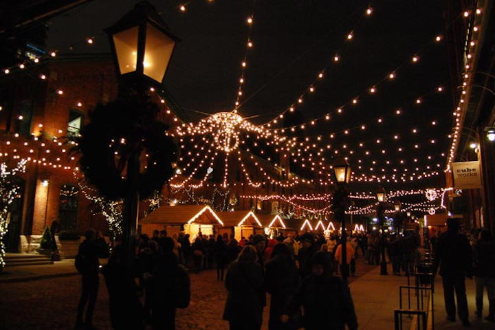 Lights hung overhead on Distillery Lane. Wooden vendor 'cabins' lined the street.