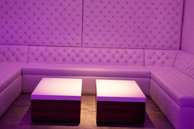 Tufted, white leather booths provide seating.