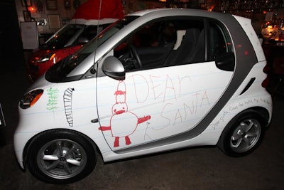 Drawings and letters written by children wrapped a white Smart vehicle, which delivered toys to children in need.