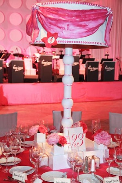 Various pink flowers and candles surrounded white and pink lamp centerpieces at each dining table.
