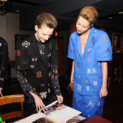 As has become a signature of Stella McCartney's festive fashion presentations, models interacted with each other, with attending guests, and with props like a photography book by the designer's late mother, Linda McCartney (pictured).