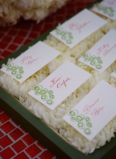 Alison Events Planning & Design arranged white dahlias in wooden trays as a display for escort cards at a birthday party.