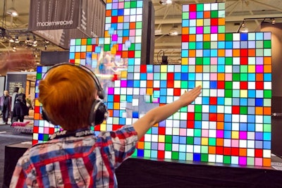 A young guest experimented with the Christie MicroTiles wall. The screens were interactive, and when guests passed in front, patterns disappeared to reveal live video feeds of themselves. The images were projected onto the wall of hanging felt strips.