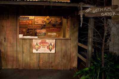 Staffers serve Cajun food prepared by chef John Folse out of a wooden structure decorated with colorful signage.