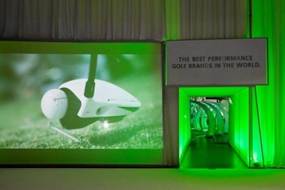 To create intrigue and control the flow of people into the booth, organizers hung white drapes across the front, leaving two tunnels for entrance and exits. Two large screens played videos showing various TaylorMade, Adidas, and Ashworth products being used on golf courses.