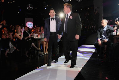 A white runner marked the aisle that ran between the guest tables to the stage.