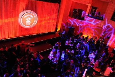 Inside the Liberty Theater's main space, guests mingled around a stage, glowing-red cocktail tables, and two bars. The platform for Ne-Yo's performance was shrouded with a gold curtain and a disc-shaped piece that matched the Malibu Red bottle label.