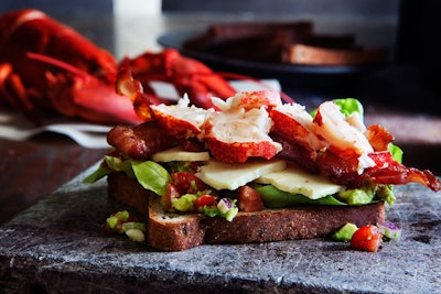 Silced Gourmet's Lobster B.L.T. is topped with cherry tomato and avocado salsa, crispy bacon, and steamed lobster.