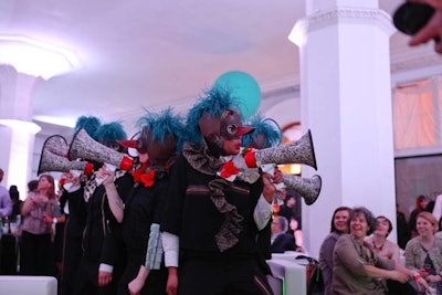 Megaphones, balloons, bird masks, and feathery caps adorned a group of performers who wandered through the V.I.P. lounge.
