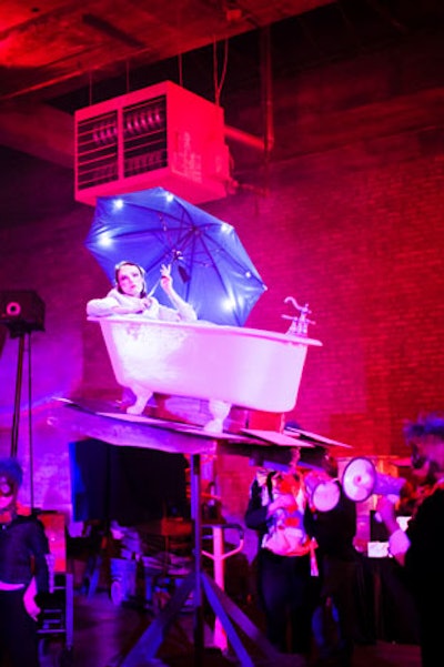 The company's 'Spinning Vehicles' are rolling platforms with elevated, performer-activated, rotating vignettes including a tilted bathtub with a bather.