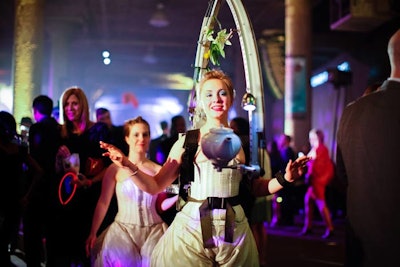 With the 'Teapot Libation Machine,' a Redmoon performer wears a metal backpack with an extended arm that holds a porcelain teapot at its end. The teapot, mechanically operated by a switch on the performer's wrist, poured cocktails into guests' glasses.