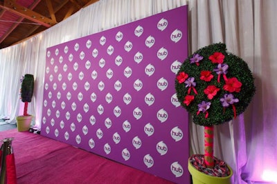 Cartoonish tree decor pieces flanked a purple press wall.