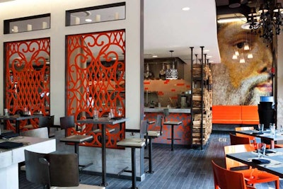 A screen of orange wall panels divides the exhibition kitchen from the main dining room.