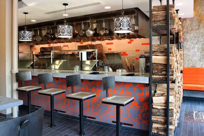 In the entryway, cords of wood are stacked on steel shelves divide the entry from the open kitchen.