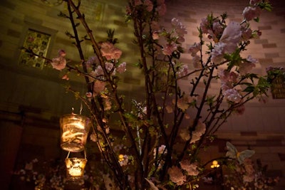 The centerpiece for each table featured more tall cherry blossoms, here more like spikes that the lilting branches of the entry installation. The votive candles were washed with some sort of bronze gilt finish, that cut the glare of the candles that often ruin this type of setup. A home run.
