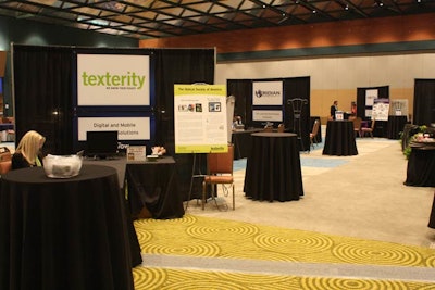 Instead of a trade show, organizers invite 12 vendors to meet with attendees at DigitalNow in a sales-free environment. Each vendor is given a table and chairs, with simple signage hanging from a black drape. Easels at each booth give a brief case study of how the vendor's product has been used successfully.