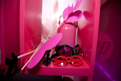 Props for the photo booth, which were placed on pink shelves inside the vignette, included masks, eyewear, hats, and items like unicorn statuettes.