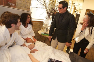 Staffers in bathrobes invited guests to pose in bed for a photo at the Mr. and Mrs. Smith launch. Signage above the bedroom setup said, 'Care to slip between our sheets?'