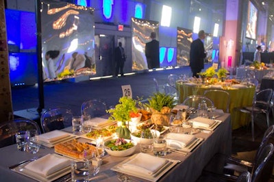 The producers hung mirrored panels to hide and reveal the sun as it rolled across the space. The tables, which were set prior to the guests' arrival, were topped with bright yellow, gray, and white tablecloths, and set with clear chairs.