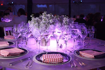 Design Cuisine provided illuminated tables accompanied by silver place settings and red- and white-striped napkins for the dinner space.