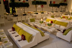 Long, communal tables and lounge-like configurations provided more relaxed seating on the upper level. For centerpieces, the designer incorporated square-shaped canopies, illuminated by candles that hung from the leaves in glass cylinders. Gift bags from sponsor Cartier were placed on guest's seats prior to the start of the event.