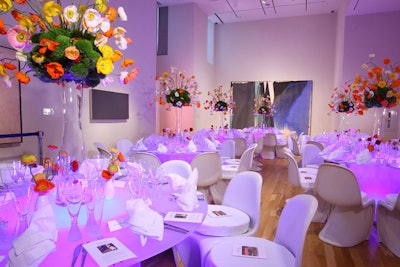 A gallery with a more contemporary design had illuminated tables and all-white chairs with sparsely populated centerpieces of orange, white, and yellow flowers.