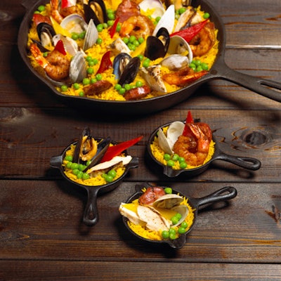 According to executive chef Chris Matthews of Eatertainment, rustic, family-style dining—exemplified by his classic paella served in mini cast-iron skillets—is currently on trend.