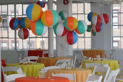 For an indoor summer-themed gathering, Swank producers used beach balls to create playful 'chandeliers.' Tables were covered in summery yellow and orange linens.