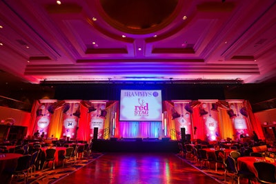 Hargrove used red, orange, and yellow drapes accented by purple top hats and lighting of the same shades from PSAV for the main stage of the grand ballroom.