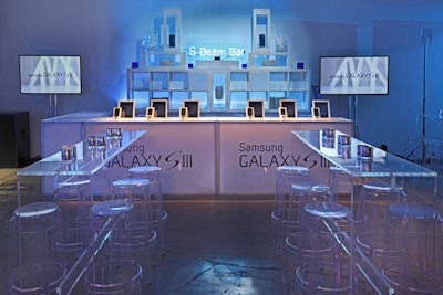 With blue lighting as the main backdrop, the event producers used white or clear furnishings for the cocktail tables, sofas, and seating. The gadget's brand imagery decorated surfaces like the facades of the bars and the venue's walls.