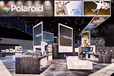 For the Polaroid space at CES 2011, Skyline Exhibits had images streaming overhead across two ribbon-screen projections, ending in the company logo. Jumbo screens framed by the Polaroid photo border surrounded a raised stage at the center of the exhibit, while a futuristic-looking lounge area with a modular mirrored exterior sat at the far end of the space.