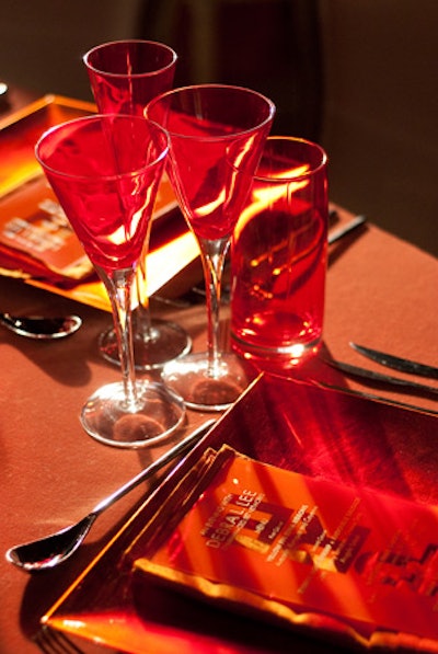 Place settings included a variation of clear and red-tinted glassware and linens in different shades of orange.