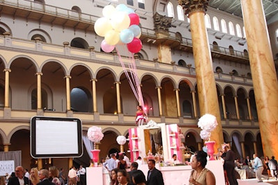 A model sat atop the centralized bar holding a bunch of oversize balloons, reminiscent of a common childhood scene near candy stores.