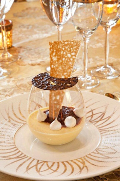 This pretty dessert from Design Cuisine is a passion fruit panna cotta garnished with malted milk meringues, topped with a chocolate cookie with gold leaf and a caramel shard inserted into the glass.
