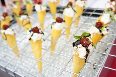 Truffleberry Market Catering has added savory ice cream cones to their offerings. Initially developed for a carnival-themed party, the hors d'oeuvre fills handmade wonton cones with creamy burrata cheese. Aged balsamic vinegar drizzled over the top resembles chocolate sauce, and a sun-dried tomato stands in for the cherry on top.