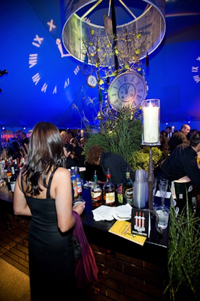 Produced by Absolute Production Services, the Green Tie Ball had three tented areas. The V.I.P. tent, called the 'Mad Hatter's Tent,' featured rustic, organic decor by Kehoe Designs. The focal point of the bar area was a giant drum shade embellished with a bronze tree, oversize pocket watches, and wine bottles. Absolute worked with Windy City Music on the lighting design, which included timepiece gobos.