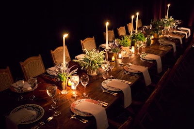 Interspersed with candlesticks and votives, rustic floral arrangements of potted herbs decorated the reclaimed wood communal tables for the dinner.