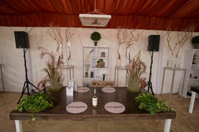 Christina Greenstein, senior manager of special events at Bon Appétit, consulted with her creative team to develop a vision for the brand's tent at the festival. 'They were looking for me to pull together an overall theme inclusive of tasting tables, furniture, and ceiling decor to attract attendees to their 80- by 16-foot tent,' said Wagner. The space housed five tasting stations and a lounge, and Wagner selected an autumnal color palate of mushroom, beige, and copper for the space. The stations had stained wood tabletops with custom acrylic insets. Landscapes growing from within the tables held broom corn, fountain grass, ferns, and fresh ivy. Vintage farm windows suspended from the ceiling added a sense of intimacy.