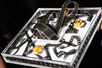 Using film as his muse, David Stark created graphics for the bar façades, step-and-repeat backdrop, and walls that utilized film cells as windows for imagery and text. Real film even decorated the catering trays that held bites from Olivier Cheng like sweet potato gratin with sage-walnut pesto on cranberry pecan toast.